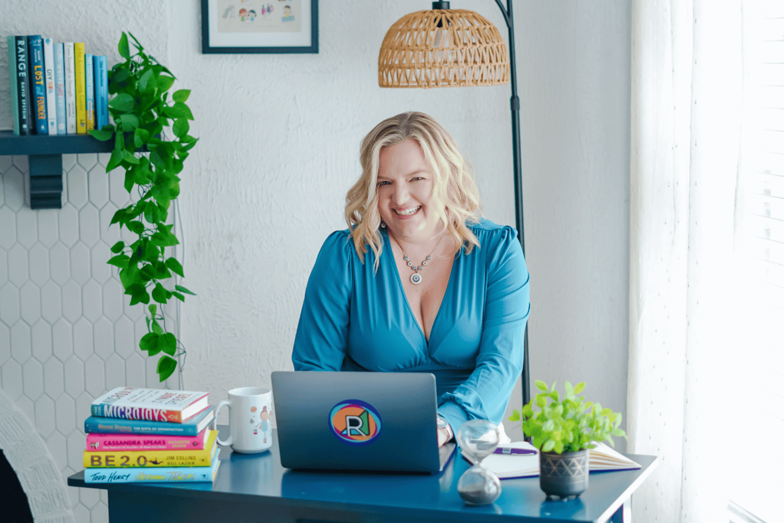 A smiling Renia typing on a laptop with a Realign Consulting stick on the back