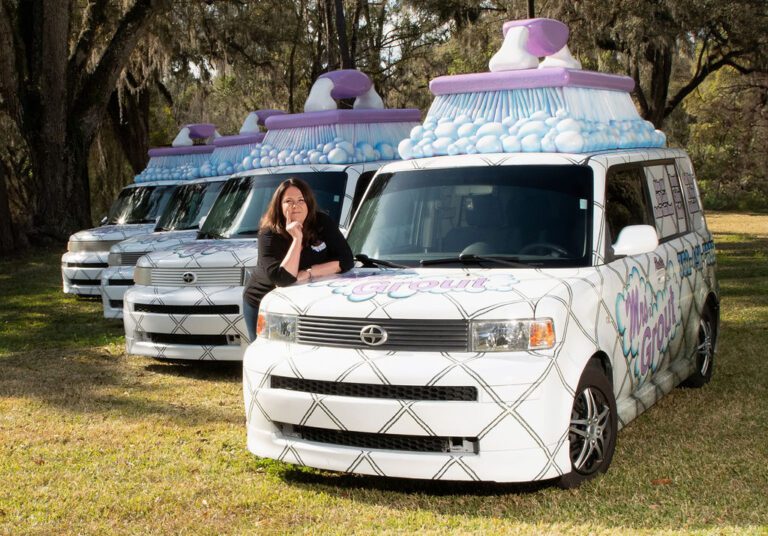 Lisa, founder of Mrs. Grout, with newly decorated Grout-mobile service vehicles. They are wrapped to look like kitchen tiles with a giant scrub brush on the roof.